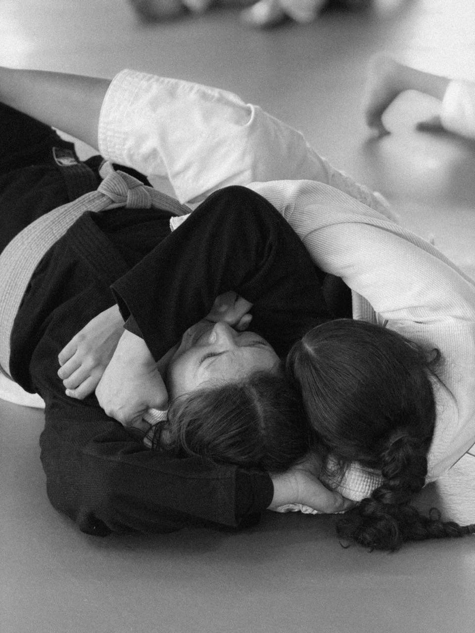 Two girls practicing controlled ground movement in kids jiu-jitsu class