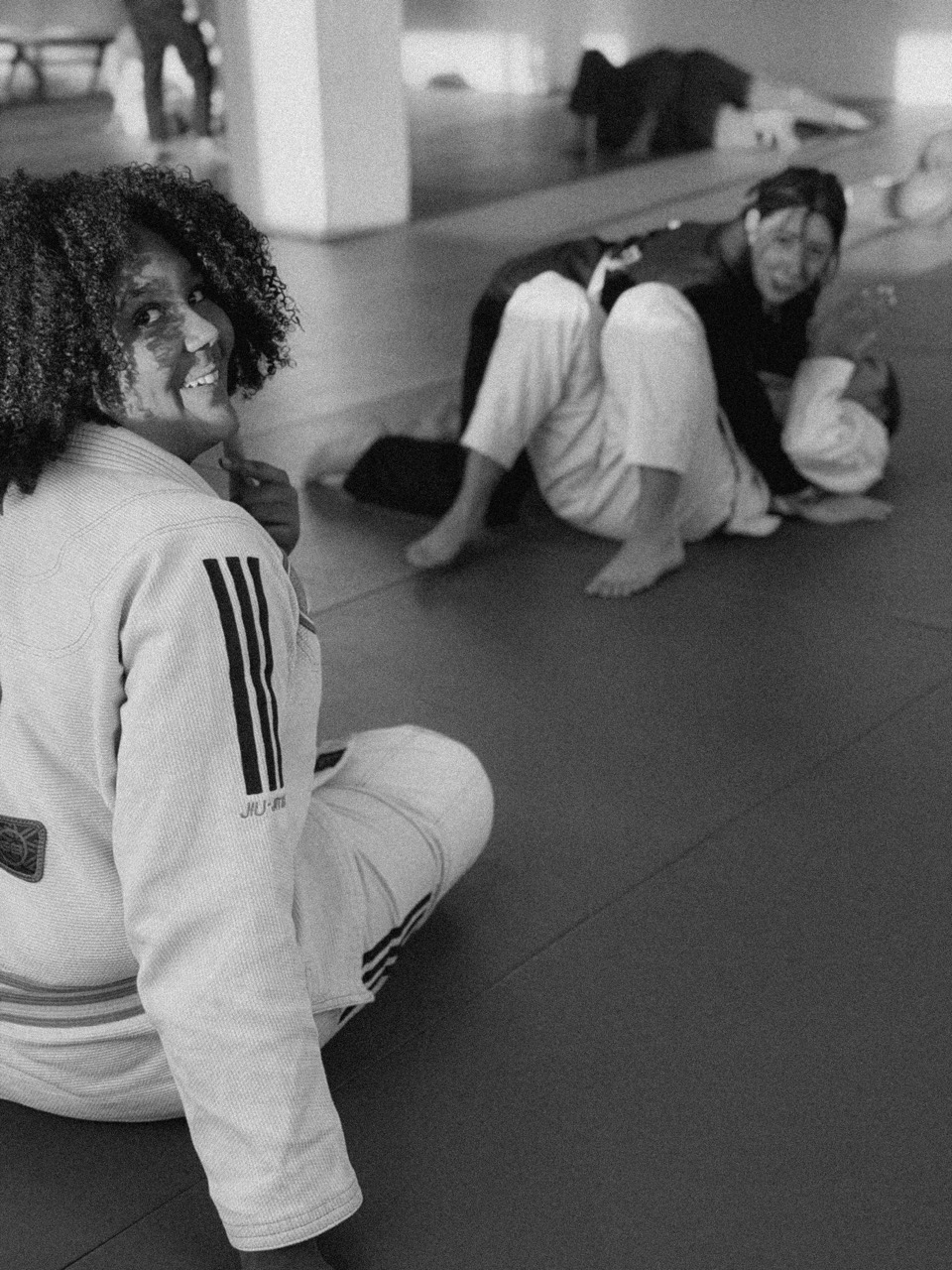 Girl smiling during a Northbound kids jiu-jitsu class with students training behind her