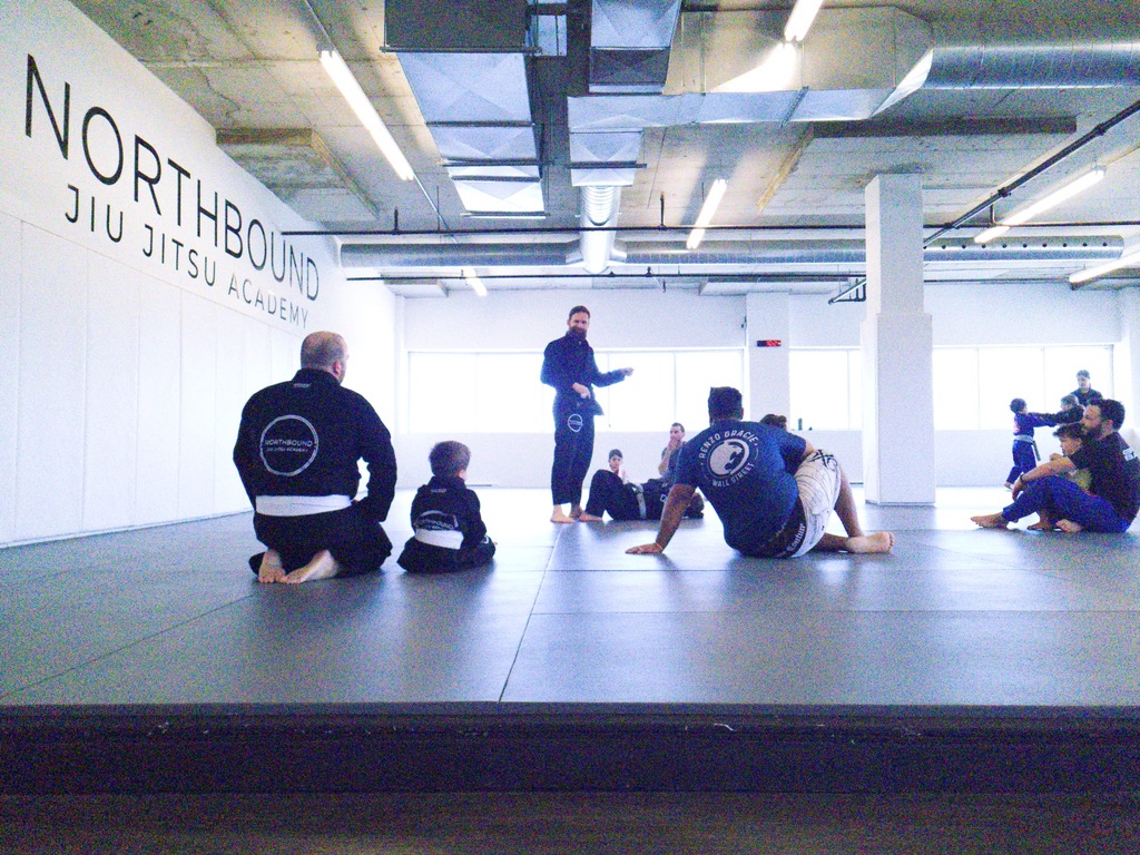 Des élèves de jiu-jitsu et un instructeur sur les tatamis de la salle lumineuse de Northbound