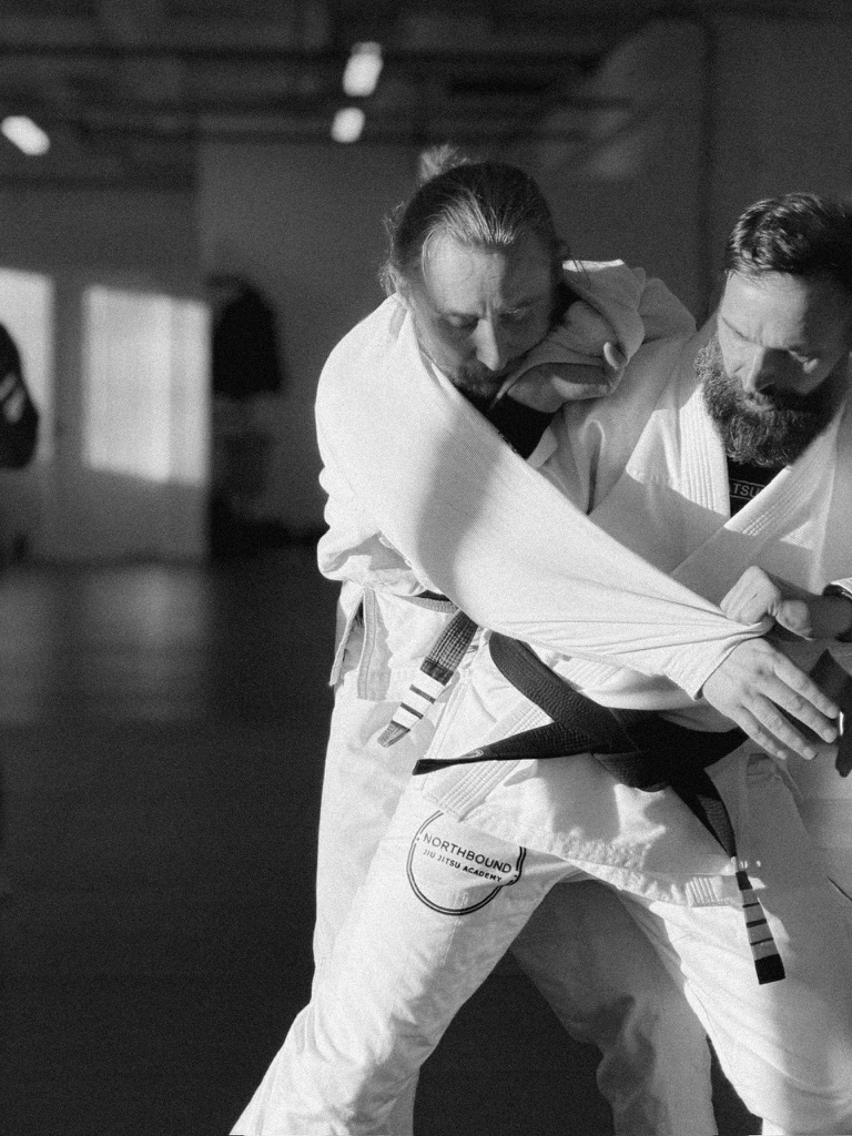 Deux partenaires de jiu-jitsu pratiquent une technique debout à la lumière naturelle